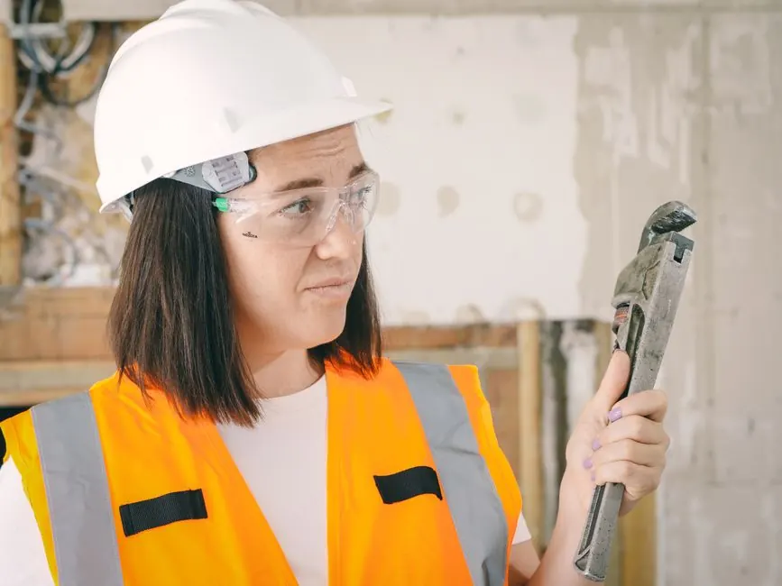 Plumber in a hard hat holding a pipe wrench