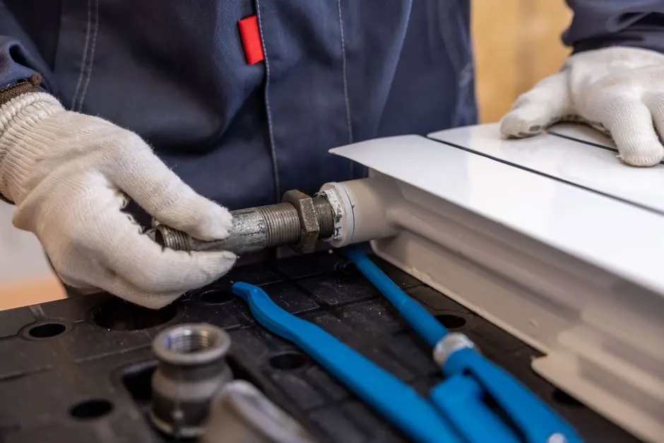 Plumber's gloved hands fitting a threaded pipe connection