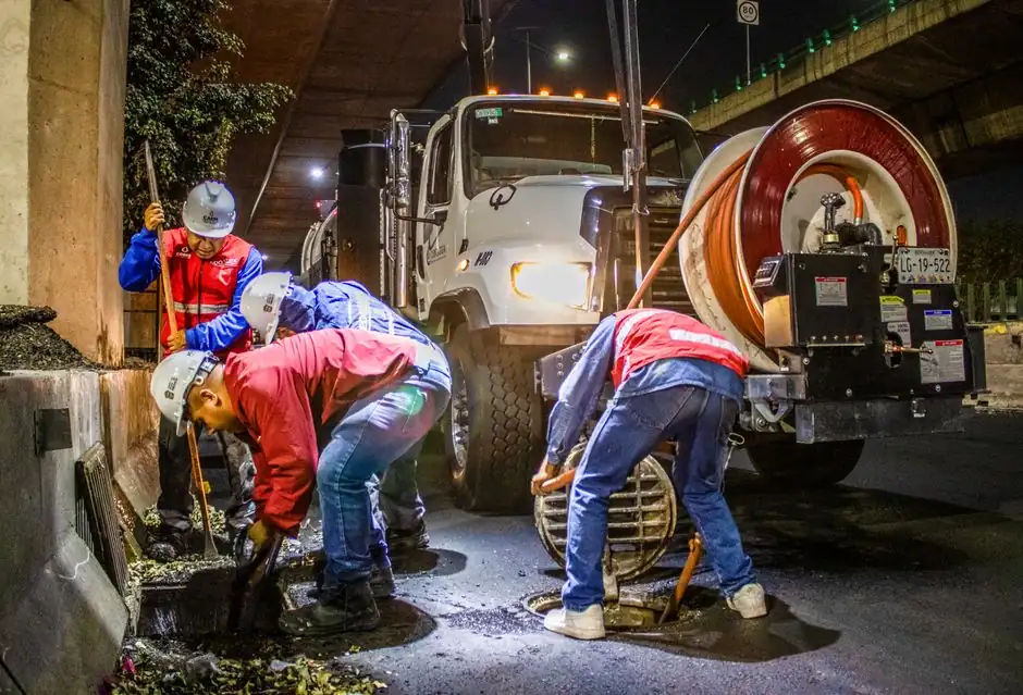 Plumbing crew clearing a sewer line with a hydro jetting truck
